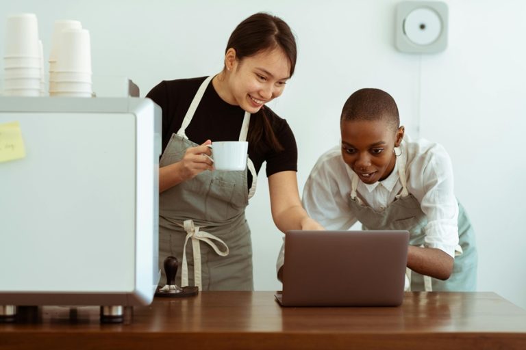 Best Small Business Marketing Company in Sewalls Point Florida Two People Looking at a Laptop While Wearing Aprons in a Small Coffee Shop