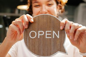 Best Google Business Profile Marketing Agency in Jupiter a Woman Holding an Open Sign Made From Wood