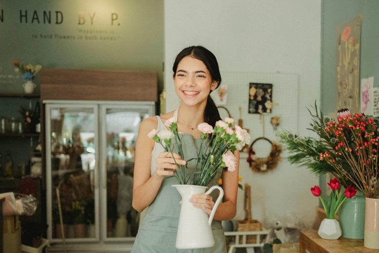 Small Business Marketing Services in North River Shores A Flower Shop Owner Standing behind a Counter in Her Store While Working on a Bouquet