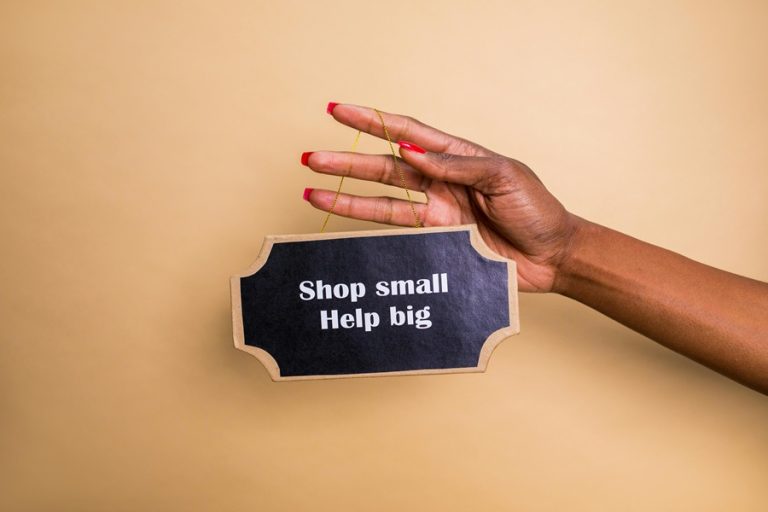 Best Treasure Coast Google Business Profile Marketing Agency a Woman's Hand Holding Up a Sign That Says Shop Small Help Big