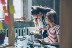 Best Small Business Marketing Company Jensen Beach Florida Two Women Working Together in an Office Over a Laptop and Some Files