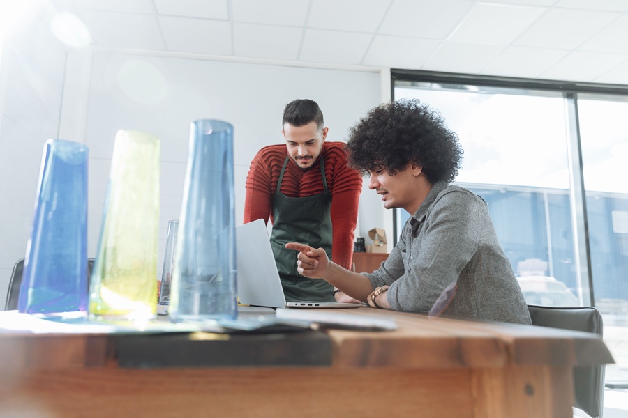 Best Small Business Marketing Services in Treasure Coast People in a Meeting with One Man Wearing an Apron and Another Person Sitting at a Desk