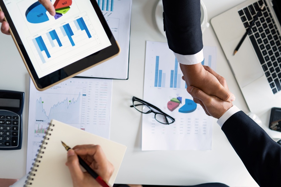 Best Google Business Profile Marketing Agency in Port Salerno Florida Two Hands Shaking Above a Table Covered in Papers with Graphs and Sales Growth Charts