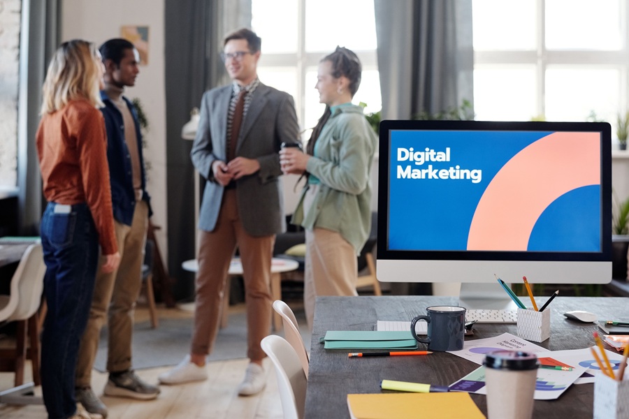 Best SEO Services in Treasure Coast a Computer That Has "Digital Marketing" on the Display with a Group of People Standing and Talking in the Background