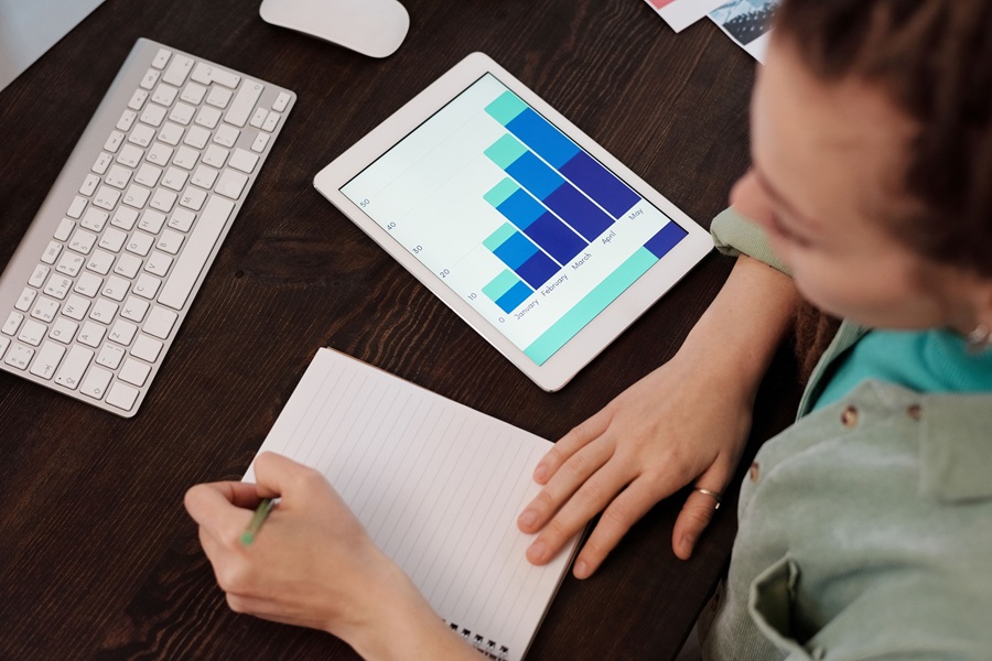 SEO Services for HVAC Companies in West Palm Beach Florida a Woman Sitting at a Desk with a Tablet That Shows a Growth Chart